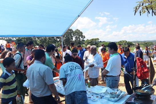 (104)年10月23日世界農糧日活動，貝國楊可為(Sr. Colville Young)總督（右三著白上衣）聽取國合會駐貝里斯水產養殖計畫周經理俊賢（右二白衣綠領）說明吳郭魚計畫並試吃。