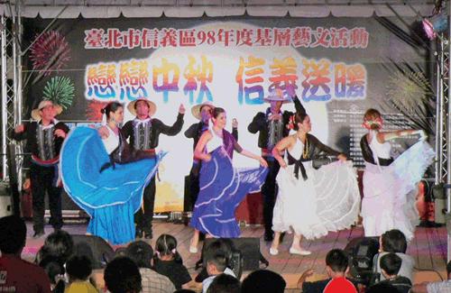 La celebración tradicional del Festival de Medio Otoño implica generalmente comer muchos pasteles de la luna; así como disfrutar de barbacoas y fuegos artificiales al aire libre mientras se contempla la luna. La Oficina del Sector de Xinyi en la ciudad de Taipei quiso que las actividades de este año tuvieran un matiz diferente, y por ello invitó a varias de las embajadas que están en la isla para que mostraran ejemplos de su cultura el 26 del mes pasado. En una explanada a la sombra del edificio Taipei 101, grupos culturales locales compartieron el escenario con grupos de estudiantes becados de Haití, República Dominicana y Paraguay. Los locales participaron con coloridas danzas de los leones, acrobacias, demostraciones de diábolos, bailes tradicionales y hasta un espectáculo de magia. Los dominicanos se lucieron bailando merengues bien movidos, mientras que un estudiante de Haití cantó un par de canciones en creole. Los estudiantes de Paraguay aportaron el plato fuerte con un bello y variado espectáculo de danzas folklóricas paraguayas, acompañadas con interpretaciones vocales y en guitarra por jóvenes de esta nación sudamericana que estudian en universidades locales. El ritmo fue muy contagioso y los taiwaneses no pudieron resistir unirse a la fiesta cuando los jóvenes paraguayos los invitaron a compartir la pista. Grandes y pequeños dieron sus primeros pasos de baile y se divirtieron mucho en una noche latina bajo la luna en Taipei. En la gráfica vemos a los estudiantes paraguayos en una de sus bien recibidas interpretaciones. (Foto de Silvia Villalobos) 