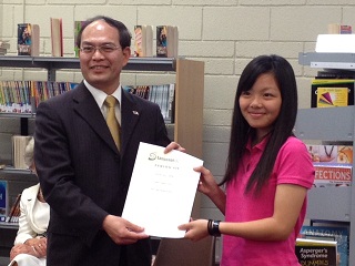 Representative Tseng presents one of the students with her certificate of graduation 