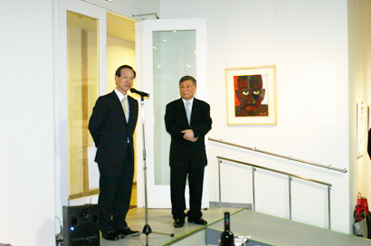 東京都台東区の「上野の森美術館」で６月２０日、台湾の画家・張耀煌（チャン・ヤオファン）さん（写真右）の「百面相」個展オープニングパーティーが開かれた。　同パーティーには台北駐日経済文化代表処の沈斯淳・駐日代表の代理として羅坤燦・駐日副代表（左）が出席し、祝辞を述べた。羅副代表は、張耀煌さんが素晴らしい画家であると同時に、成功した企業家であることに敬意を示し、「その作品は人間の驚き、悲しみ、怒り、喜びなど顔の表情がよく表現されている」と述べ、個展の成功を祝福するとともに、今後ますます台日芸術交流が深まり、より多くの台湾の芸術家が日本で作品を展示できるよう期待を示した。