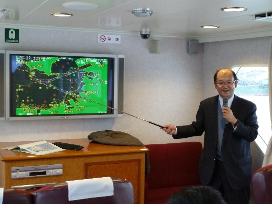 國土交通省九州地方整備局博多湾・空港整備事務所酒井浩二所長在船上解說博多港