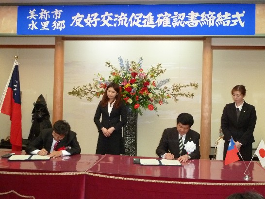 南投縣水里鄉江龍漢鄉長與山口美禰市村田弘司市長簽署備忘錄情形。