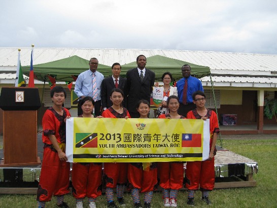 曹大使(後左2)、青年部部長Glenn Phillip(後中)、次長Curt Lewis(後右1)、廳長Geoffrey Hanley(後左1)、青年大使團領隊許助理教授淑媖(後右2)及青年大使學生(前排)於雙方互贈校旗後合影留念。