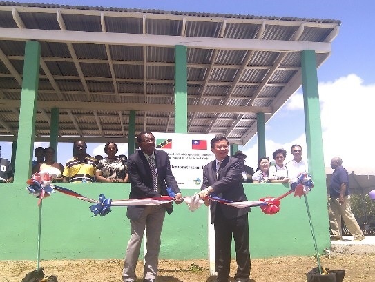 104年8月14日駐聖克里斯多福及尼維斯丘大使高偉（右）與聖克里斯多福及尼維斯農業部長Eugene Hamilton（左）共同為「蔬果雜糧作物品質與產安全改進計畫」新完工之堆肥示範場剪綵啟用