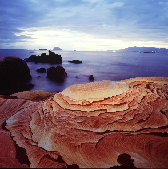 一隙曙光柔和地鋪陳在臺灣北部海岸的海蝕砂岩上，點綴了石紋之美。(顏明邦　拍攝)