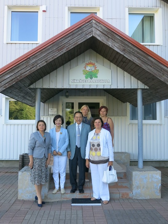 葛大使夫婦、國會議員克林伯格(右一，Nelly Kleinberg)、斯克倫達(Skrunda)市長羅柏絲尼采(左一，Loreta Robezniece)與Nikrace小學校長及教師合影