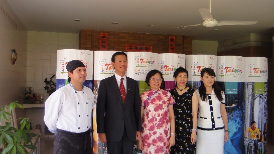 2011.02.01 黃大使夫婦與駐館館員眷屬、職務宿舍廚師合影（背景為觀光局所供台灣旅遊大型直立牌）。