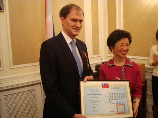 張代表小月2011年2月8日上午代表中華民國外交部在本處頒贈英國「貿易文化辦事處（BTCO）」前代表麥瑞禮（Dr. Michael Reilly）「睦誼外交獎章」及證書，表彰駐華期間積極促進台英關係。