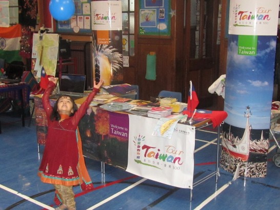 參觀世界日活動的小朋友開心的在台灣攤位前玩我國慶祝國慶氣球。