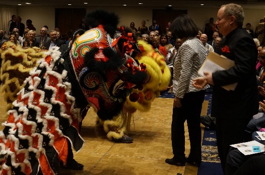 Deputy Representative Hung and NPC President Belkind give red envelopes as a symbol of good luck to the lion dance, one of the international performances at the International Cultural Evening on November 19, 2014.