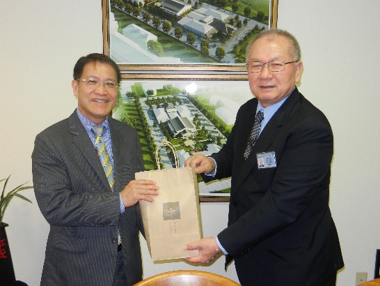 Mr. Huang of Tzu Chi presents a gift, including a copy of the Tzu Chi Medical Journal to Director General Liao