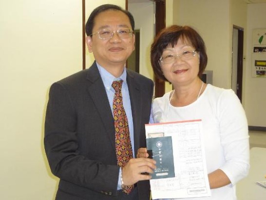 -	Secretary Chang pictured with passport renewal applicant Ms. Wang.