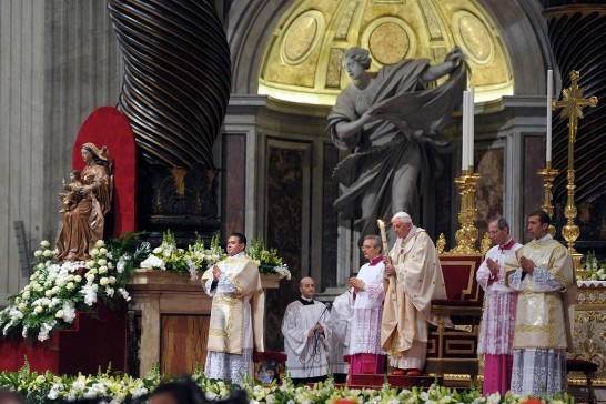 The Holy Fathers prays while holding a lit candle in his hands