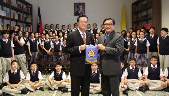 School Director Chih-Chi Ko (right) gives a pennant of Taipei Fu-Hsing Private School as a token of friendship to Ambassador Larry Wang (left).