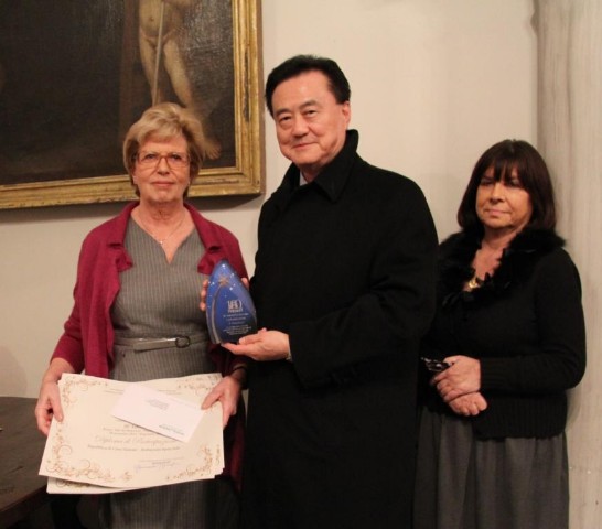 Director Maria Carla Menaglia (left) delivers the “Third Best Nativity Scene” Award to Ambassador Larry Wang (middle).