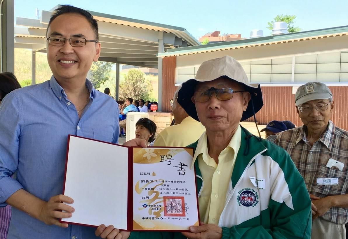 張詩瑞處長代客家委員會轉頒諮詢委員聘書給僑務顧問劉義芳，由夫婿姚火草先生代表接受