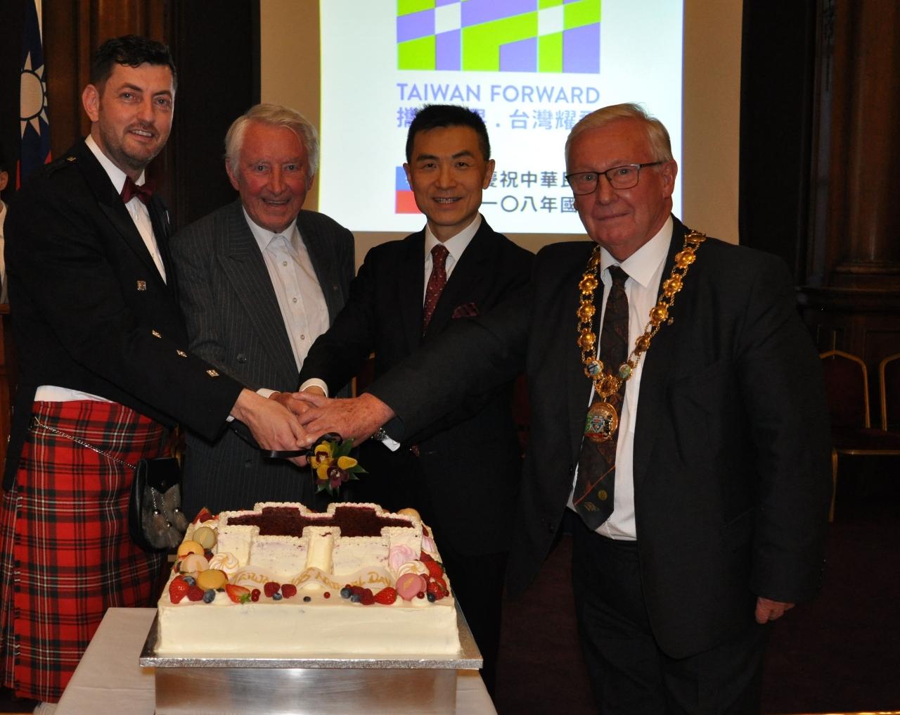 蘇格蘭西洛錫安市市長柯爾（右1）、愛丁堡辦事處處長連建辰（右2）、前英國國會友台小組共同主席上議院議員史蒂爾勳爵（左2）及愛丁堡市議會副議長戴伊（左1）合切國慶蛋糕。