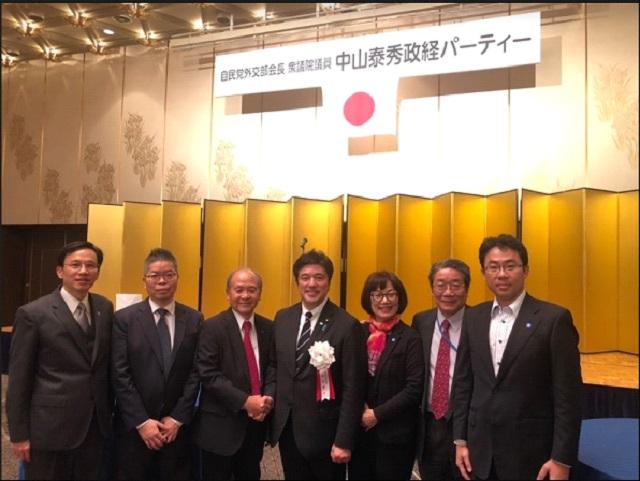 林部長（左2）、羅課長（右2）、謝課長（右1）、洪勝信・大阪中華総会会長（左3）、林所長（左1）、中山衆議院議員（中央）らの集合写真