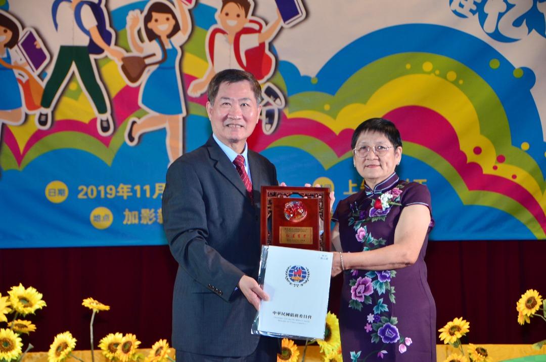 Deputy Representative Michael S.Y.Yiin (left) gives the OCAC trophy to Joon Mee Chin, the teacher who has served in Chung Hua Middle School No.1 for 50 years.