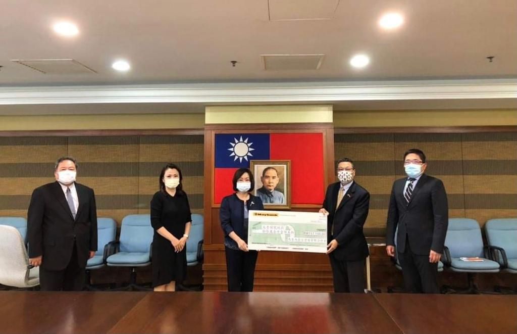 Lin Young Chang,the president of TIAM, gives the donation mock cheque to Representative Anne Hung.

