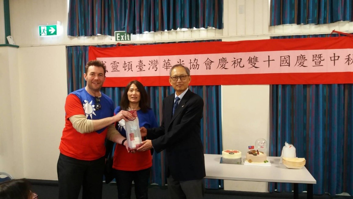 陳代表（右）贈紀念品予穿國旗裝之國人及配偶