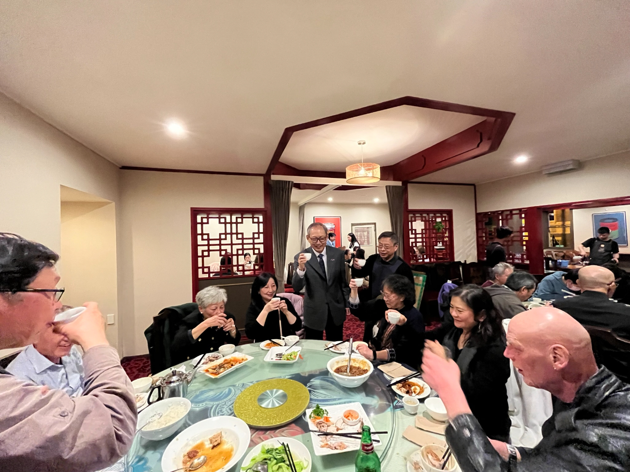 陳代表（中立者）及華聲協會蒲俊維會長暨僑務顧問（右立者）向僑胞敬酒寒暄