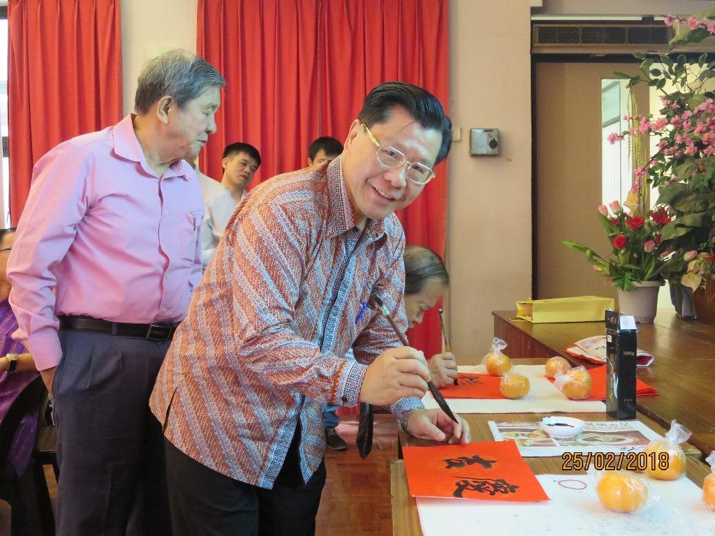 Representative Francis Liang writing his Chinese New Year message on red paper.