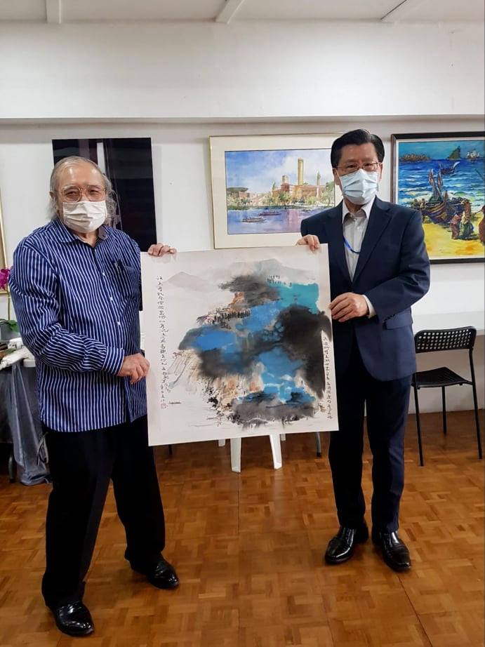 Chairman of the Federation of Art Societies (Singapore) Mr. Stephen LEONG  Chun Hong (left) handling an art painting to Representative LIANG. (28/08/2021)